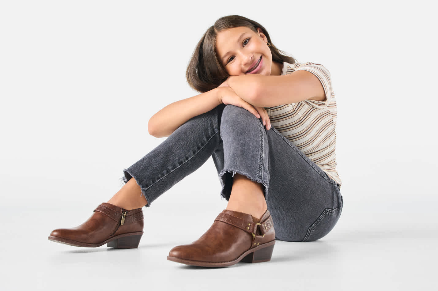 A happy young women sitting on the floor and resting her head on knees is wearing rugged boots