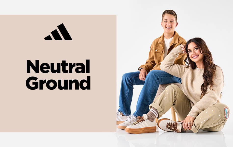 A Mom wearing adidas VL Court Bold sneakers sitting on the ground next to her son who is wearing adidas Barreda sneakers.