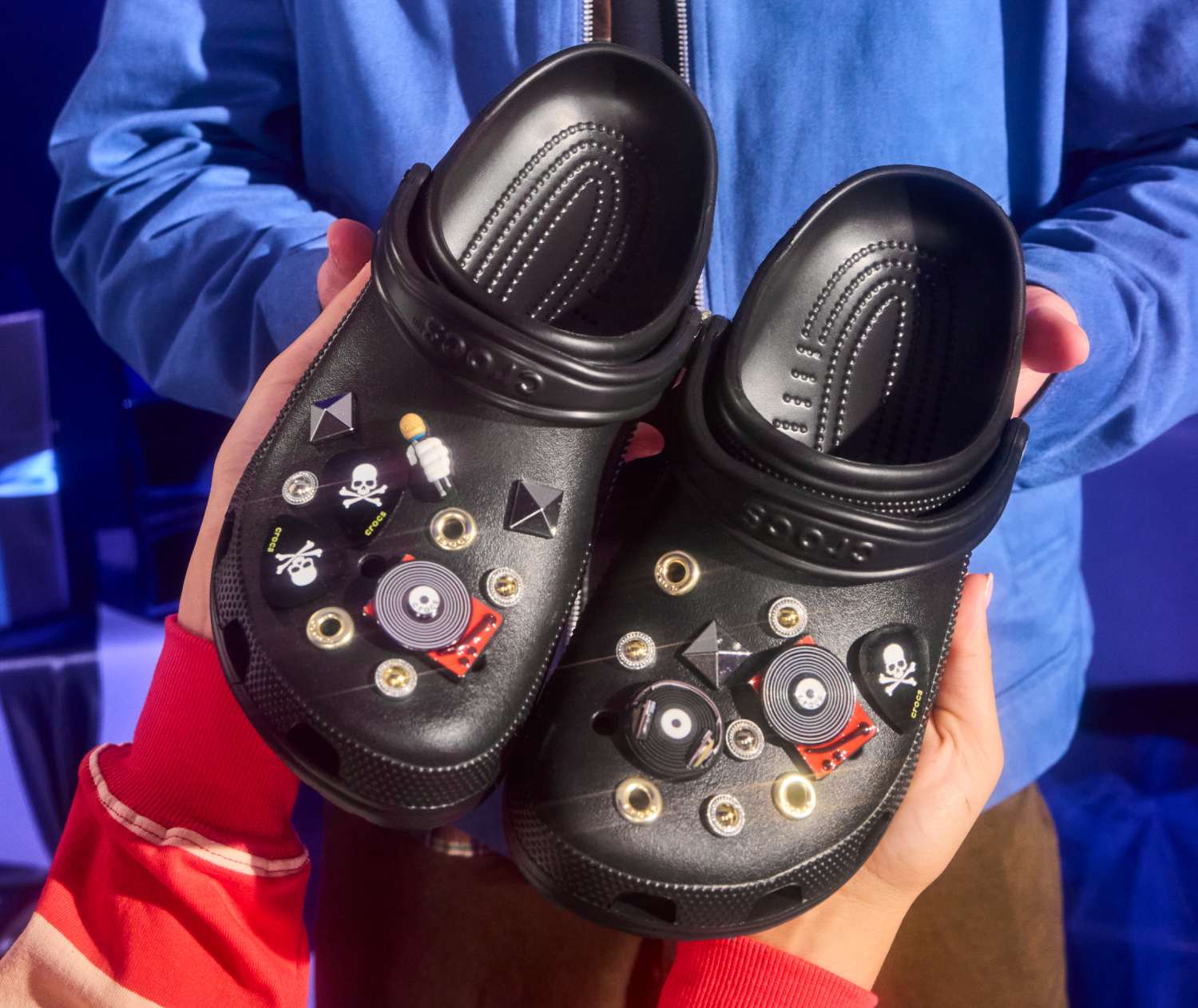 Photo of a man wearing glasses receiving a pair of black Crocs unisex classic clogs with decorative Jibbitz.