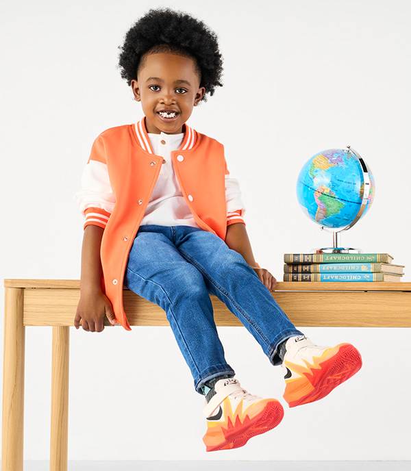 A joyful boy sitting on table wearing nike sneakers
