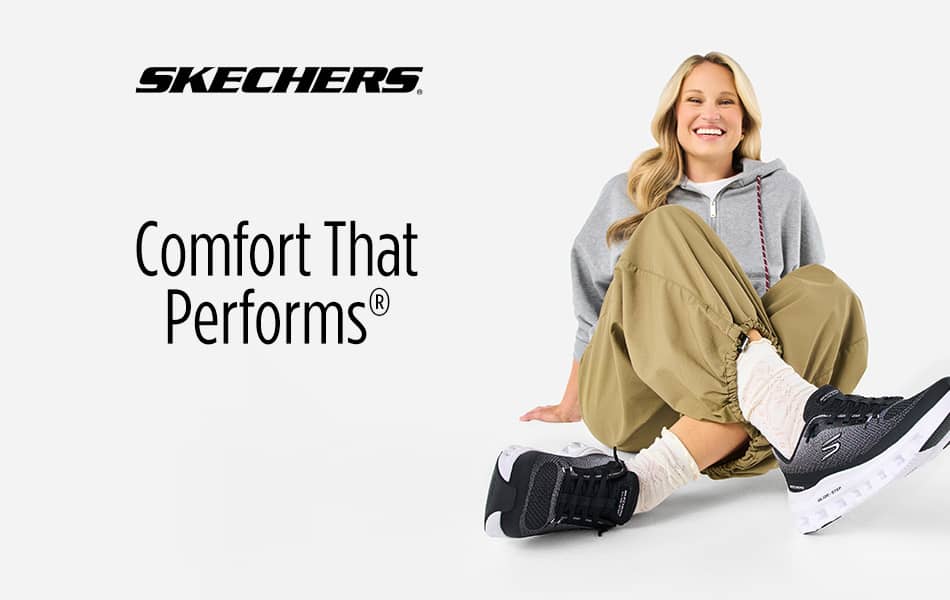 Woman sitting with legs crossed with right foot pointed and left tucked under in a pair of Skechers.