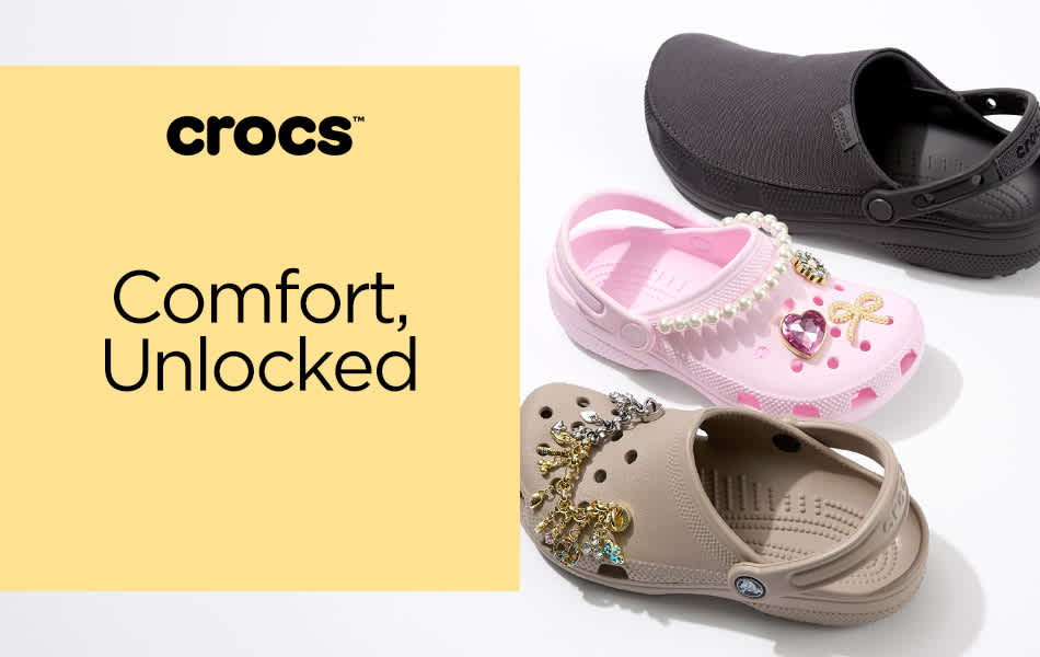 Three different Crocs clogs in a line, black, pink and brown with the last two having personalized Jibbitz.