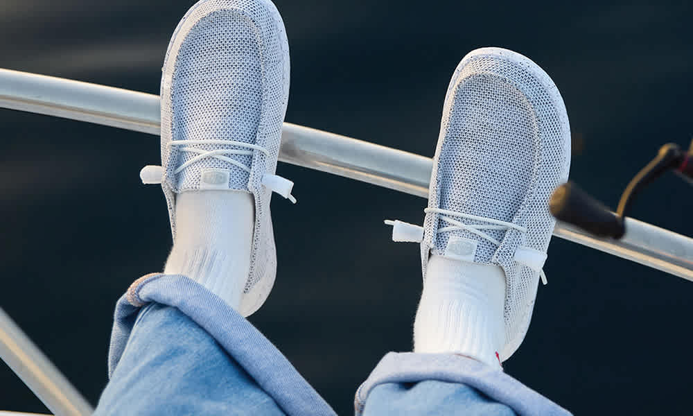 A mom, dad and their young daughter jumping for joy while wearing trendy and comfy athletic sneakers.
