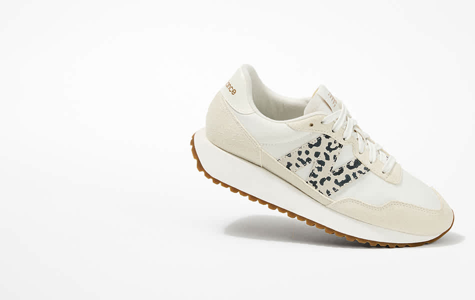 Hero shot of a women's white New Balance 237 sneaker with leopard print logo on a white background.