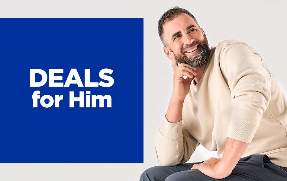 A young bearded man smiling sitting on a folding chair looking to the side.
